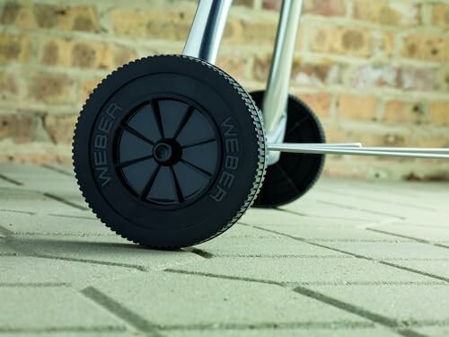 Close-up of grill wheels on a patio.