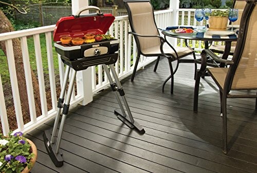 Portable grill on deck with food and patio furniture.