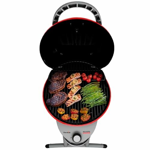 Open portable grill with steaks, vegetables, and skewers.